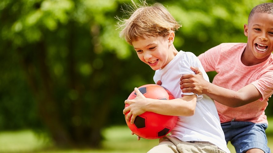 Jungen beim Fußballspiel Zwei Jungen rangeln lachend um Fußball